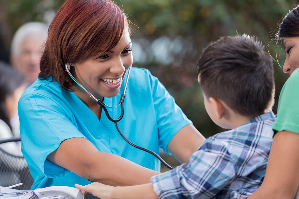 Cheerful Nurse Checks Boy's Heartbeat at Free Outdoor Clinic
